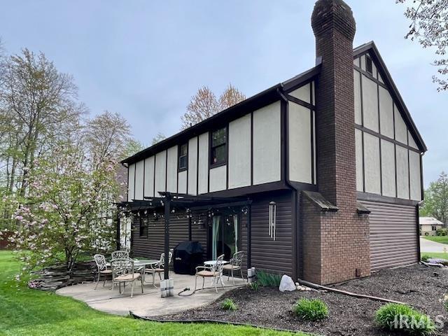 6827 Belle Plain Cv, Fort Wayne, IN 46835 - rear view of house featuring a pergola, brick siding, board and batten siding, a chimney, and a patio