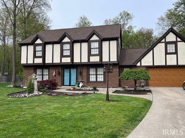 6827 Belle Plain Cv, Fort Wayne, IN 46835 - tudor home with a front lawn, roof with shingles, stucco siding, and concrete driveway