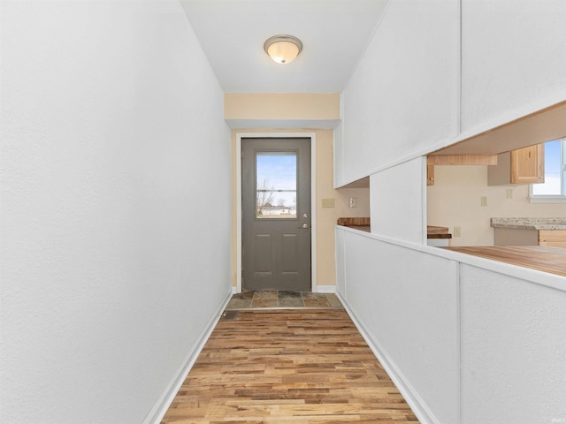 doorway with baseboards and light wood-style floors