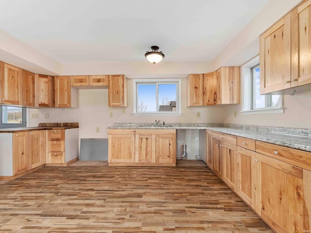 kitchen with light brown cabinets, a sink, and light wood finished floors