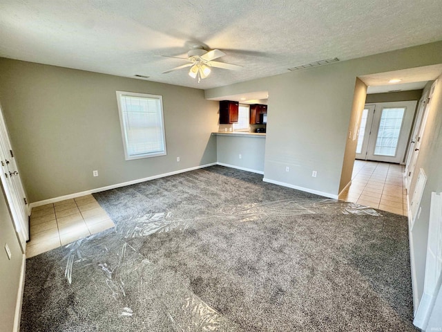 unfurnished living room with carpet flooring, tile patterned flooring, and ceiling fan
