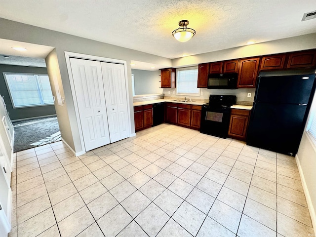kitchen featuring a textured ceiling, visible vents, black appliances, light countertops, and light tile patterned floors