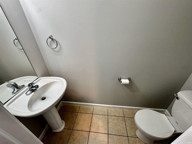half bathroom featuring baseboards, tile patterned flooring, and toilet