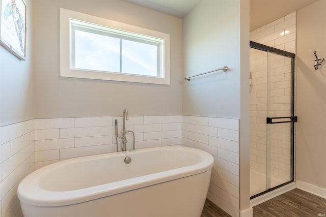 bathroom with tile walls, wood finished floors, a shower stall, and a freestanding bath