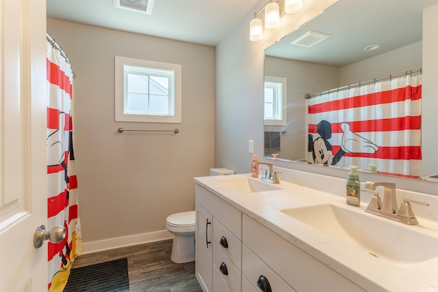 bathroom with toilet, wood finished floors, a sink, and visible vents