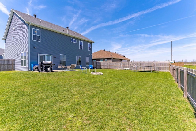 rear view of house featuring a fenced backyard, a fire pit, a yard, and a patio