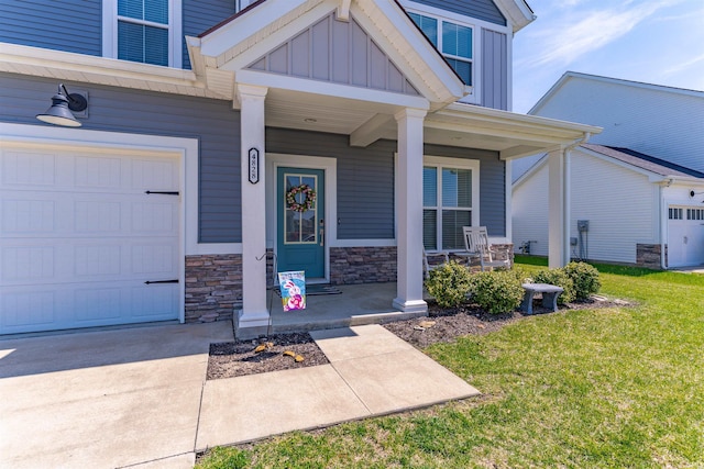 doorway to property featuring driveway, stone siding, board and batten siding, covered porch, and a yard