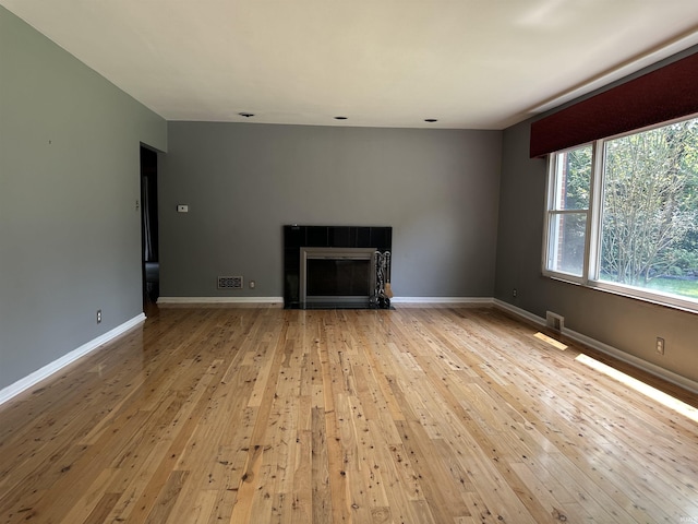 6065 Gladden Dr, Indianapolis, IN 46220 - unfurnished living room with a tiled fireplace, visible vents, baseboards, and light wood-type flooring