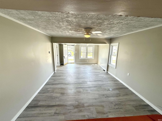 interior space with wood finished floors, baseboards, ceiling fan, and crown molding