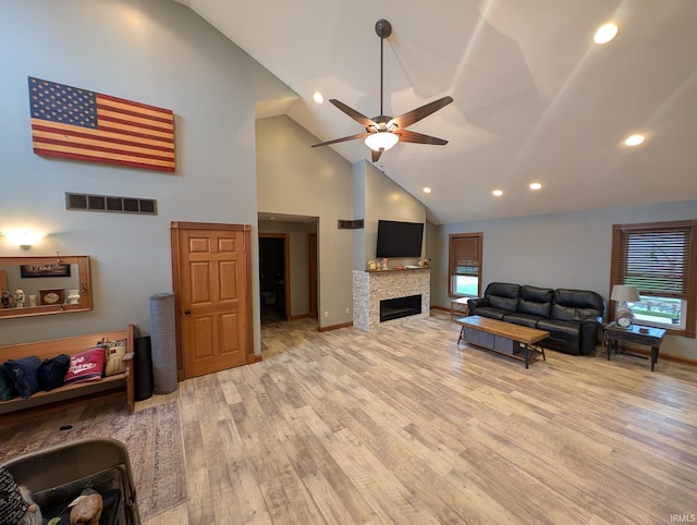 living room with a wealth of natural light, a ceiling fan, visible vents, and high vaulted ceiling