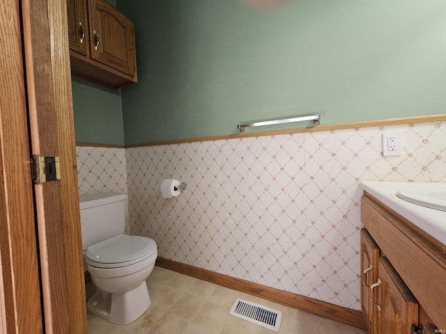 bathroom featuring vanity, tile walls, a wainscoted wall, toilet, and visible vents