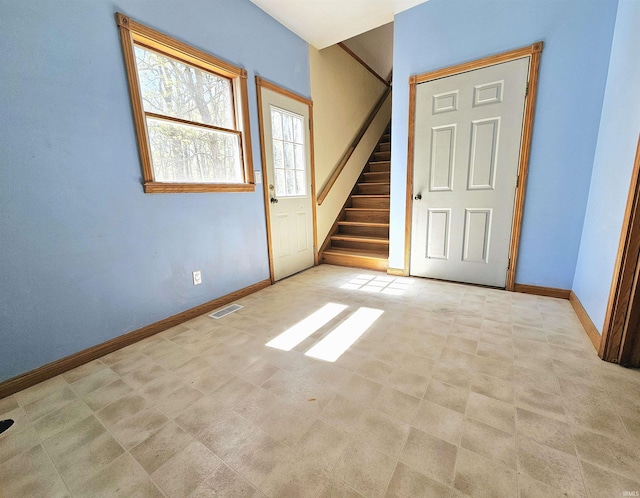 interior space featuring baseboards, visible vents, and stairway