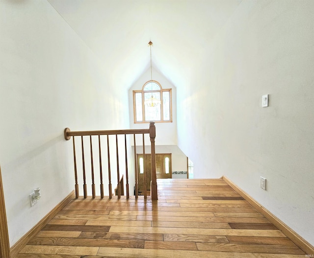 staircase featuring baseboards, lofted ceiling, and hardwood / wood-style flooring