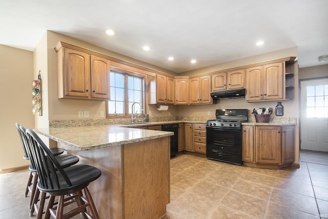 kitchen featuring recessed lighting, under cabinet range hood, a breakfast bar, black appliances, and a peninsula