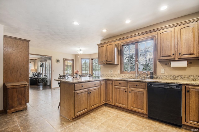 kitchen featuring recessed lighting, dishwasher, a sink, light stone countertops, and a peninsula