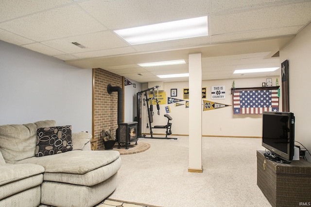 living room featuring a wood stove, a paneled ceiling, visible vents, and carpet floors