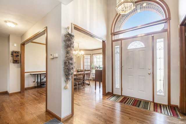 foyer with wood finished floors, baseboards, and an inviting chandelier