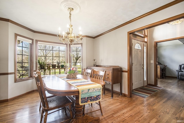 dining room featuring ornamental molding, baseboards, a notable chandelier, and light wood finished floors