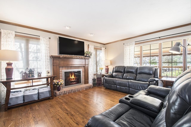 living area with wood finished floors, a brick fireplace, and ornamental molding