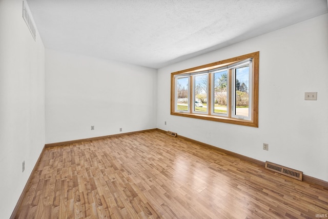 spare room featuring baseboards, visible vents, and light wood-style flooring