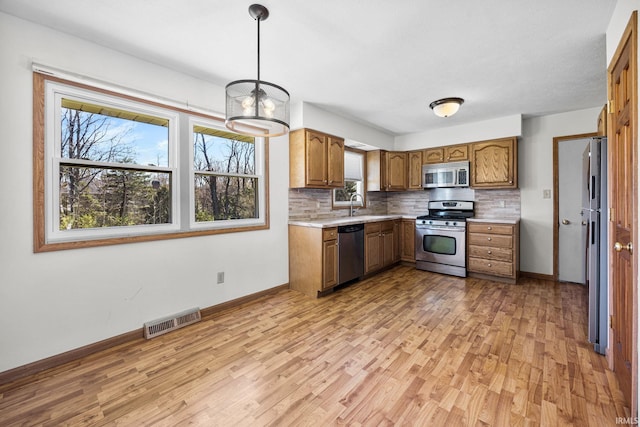 kitchen with brown cabinets, light wood-style floors, visible vents, and stainless steel appliances