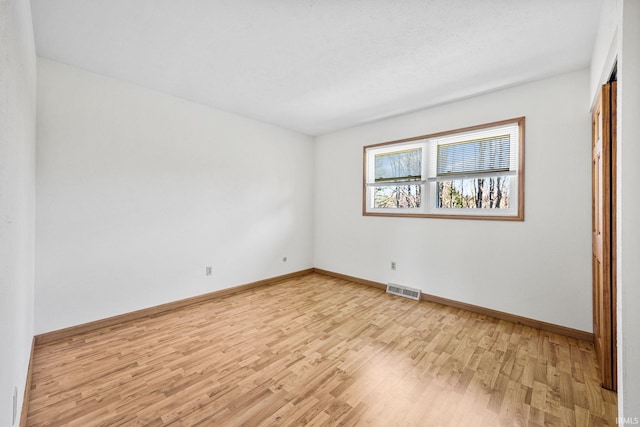 empty room featuring baseboards, visible vents, and light wood-style floors