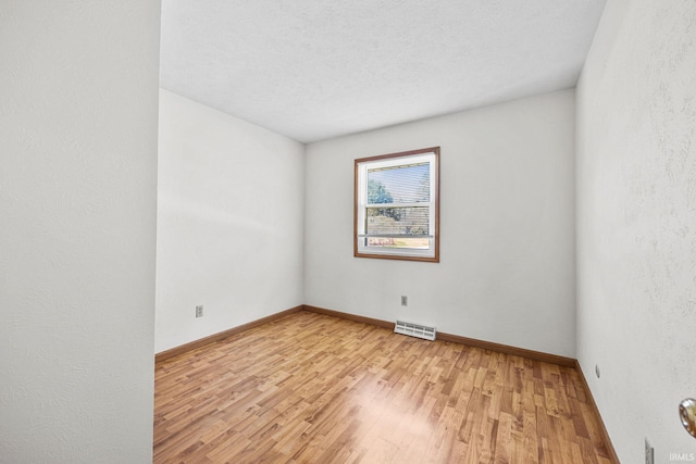empty room with light wood-type flooring, baseboards, and visible vents