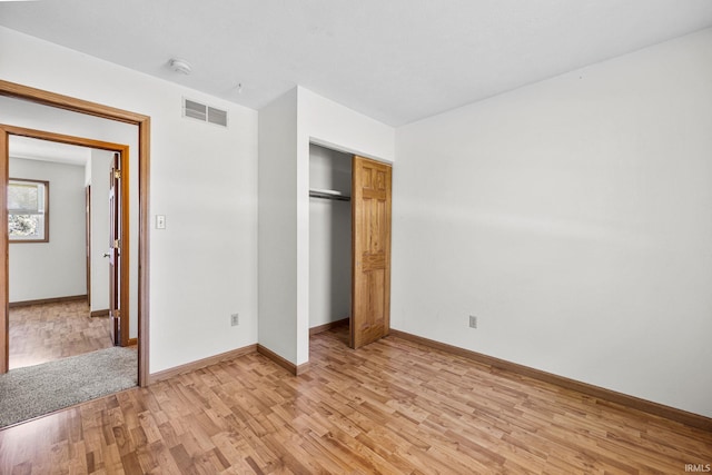unfurnished bedroom with light wood-style floors, a closet, baseboards, and visible vents