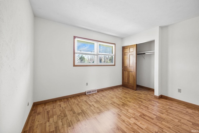 unfurnished bedroom with baseboards, a closet, visible vents, and light wood-type flooring