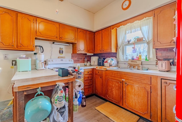 kitchen featuring tasteful backsplash, a sink, brown cabinetry, light wood-type flooring, and light countertops