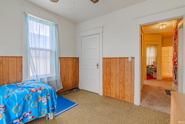 carpeted bedroom with wainscoting, wood walls, and visible vents