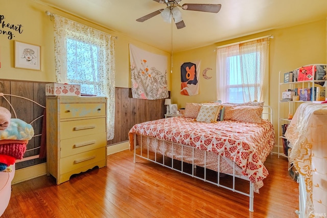 bedroom featuring a ceiling fan, a wainscoted wall, and wood finished floors