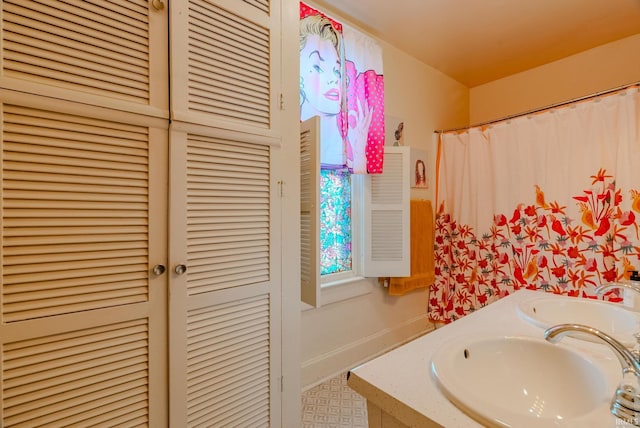 bathroom with double vanity, baseboards, and a sink