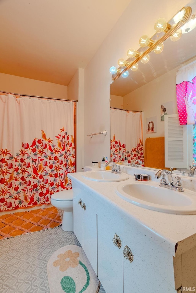 bathroom with a sink, double vanity, and toilet