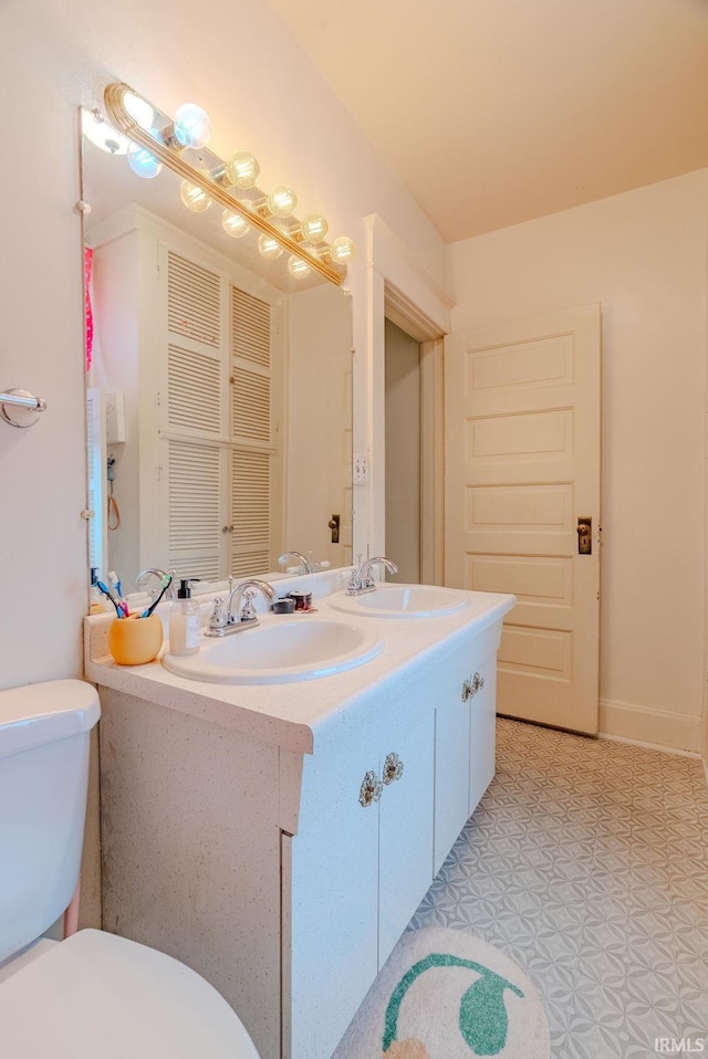 full bathroom with toilet, a sink, and double vanity