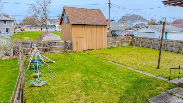 view of yard with a shed, a playground, a fenced backyard, a garage, and a residential view