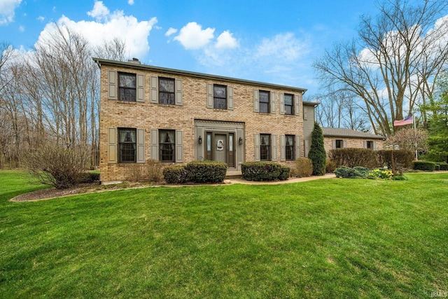 colonial home featuring brick siding and a front lawn