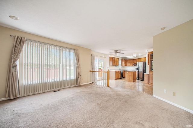 22486 Fireside Dr, Goshen, IN 46528 - unfurnished living room with visible vents, a ceiling fan, baseboards, and light carpet