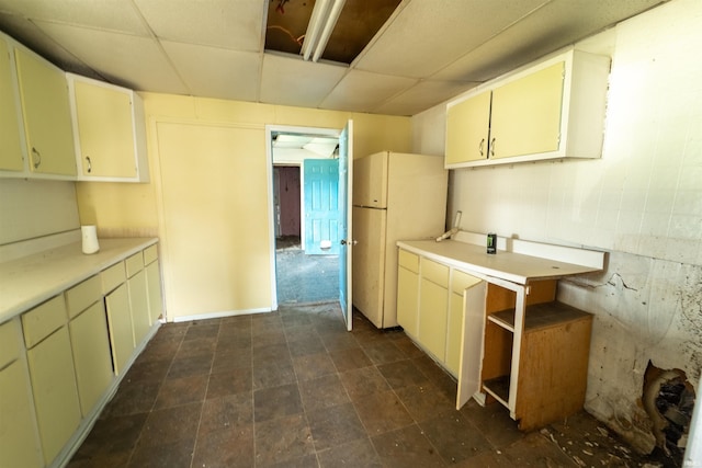 kitchen featuring light countertops, freestanding refrigerator, and a drop ceiling