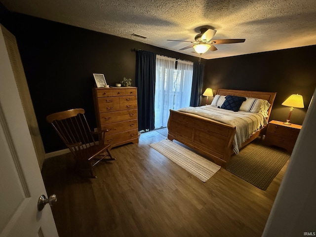 bedroom with wood finished floors, visible vents, baseboards, a textured ceiling, and ceiling fan