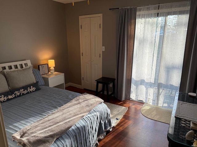 bedroom featuring baseboards, wood finished floors, and a closet