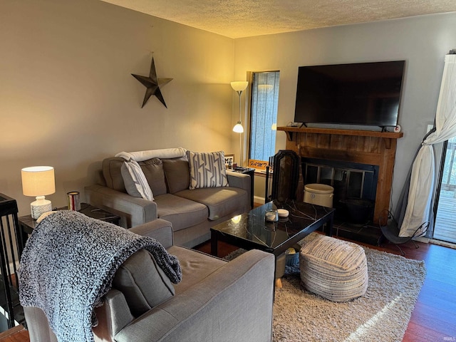 living room featuring a glass covered fireplace, wood finished floors, and a textured ceiling