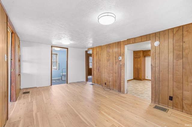 8763 E Backwater Rd, North Webster, IN 46555 - empty room featuring a textured ceiling, visible vents, light wood finished floors, and wood walls