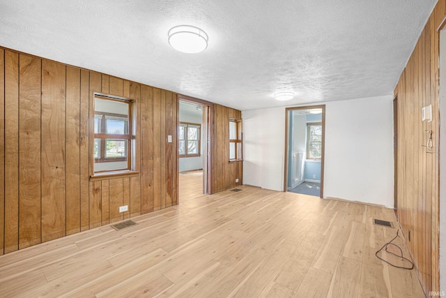 8763 E Backwater Rd, North Webster, IN 46555 - empty room with wood walls, light wood finished floors, a textured ceiling, and visible vents