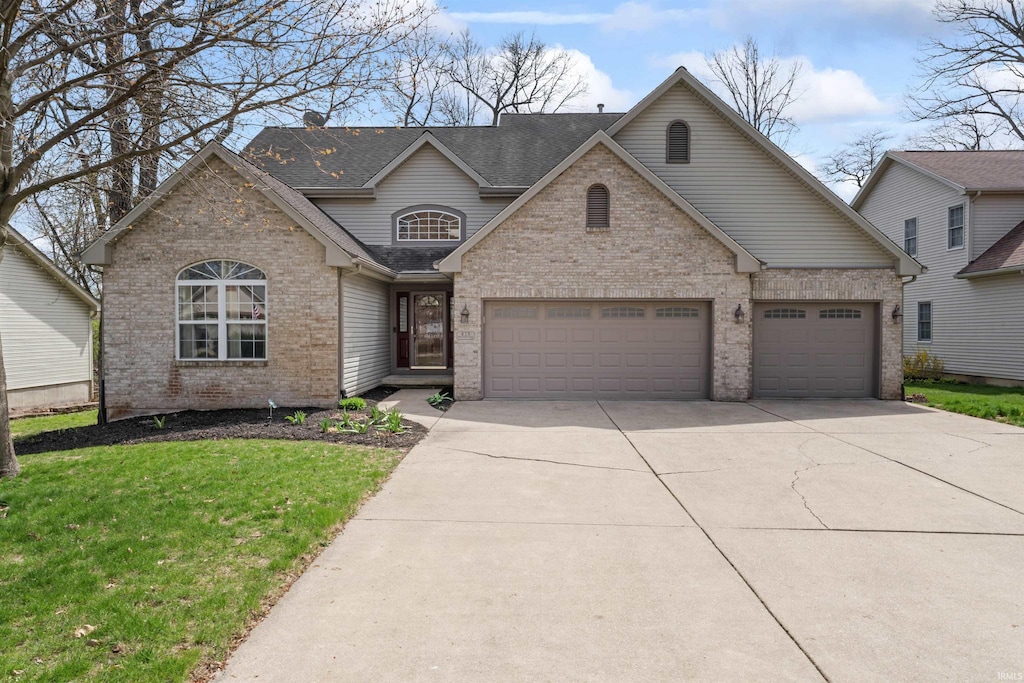 traditional home featuring a shingled roof, a front lawn, concrete driveway, brick siding, and a garage
