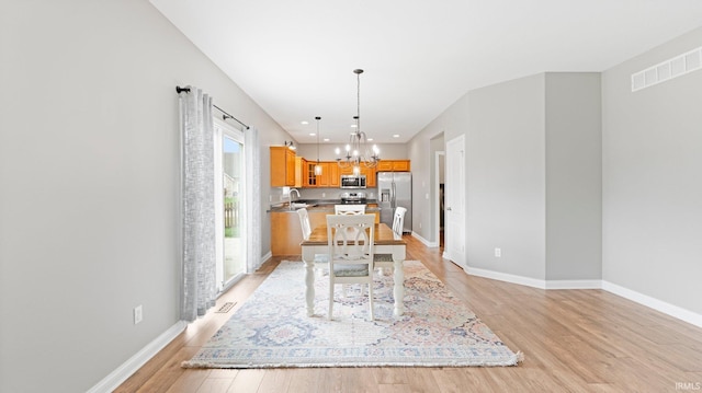 dining space featuring baseboards, visible vents, an inviting chandelier, and light wood-style floors