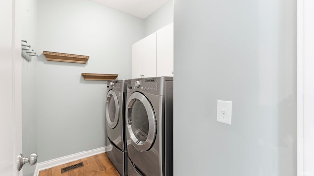clothes washing area with wood finished floors, cabinet space, baseboards, visible vents, and independent washer and dryer