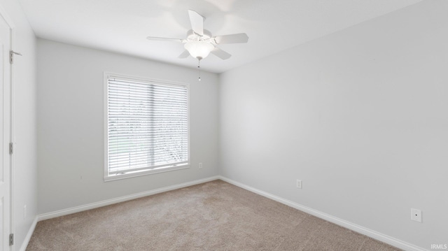 empty room with a wealth of natural light, carpet flooring, baseboards, and a ceiling fan