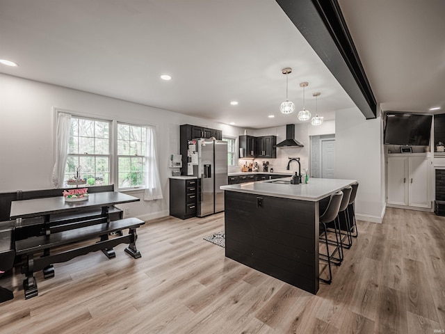 8013 Larch Ln, Evansville, IN 47710 - kitchen with dark cabinets, light countertops, wall chimney range hood, a sink, and stainless steel refrigerator with ice dispenser