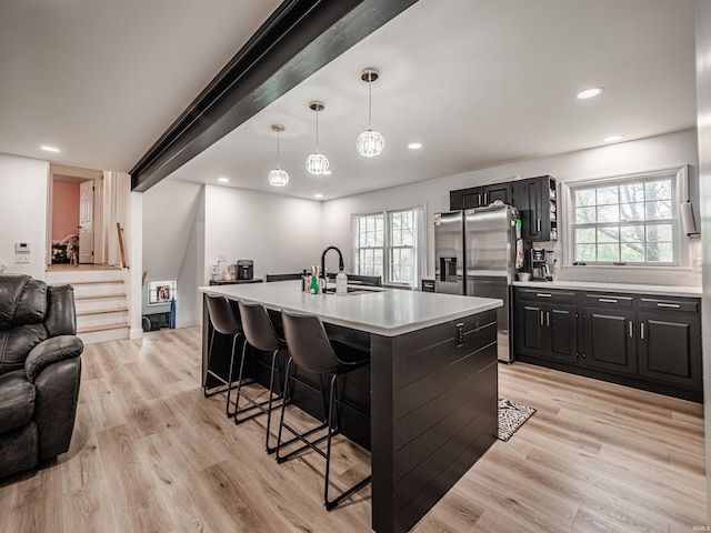 8013 Larch Ln, Evansville, IN 47710 - kitchen featuring a sink, open floor plan, stainless steel fridge with ice dispenser, light countertops, and a kitchen bar